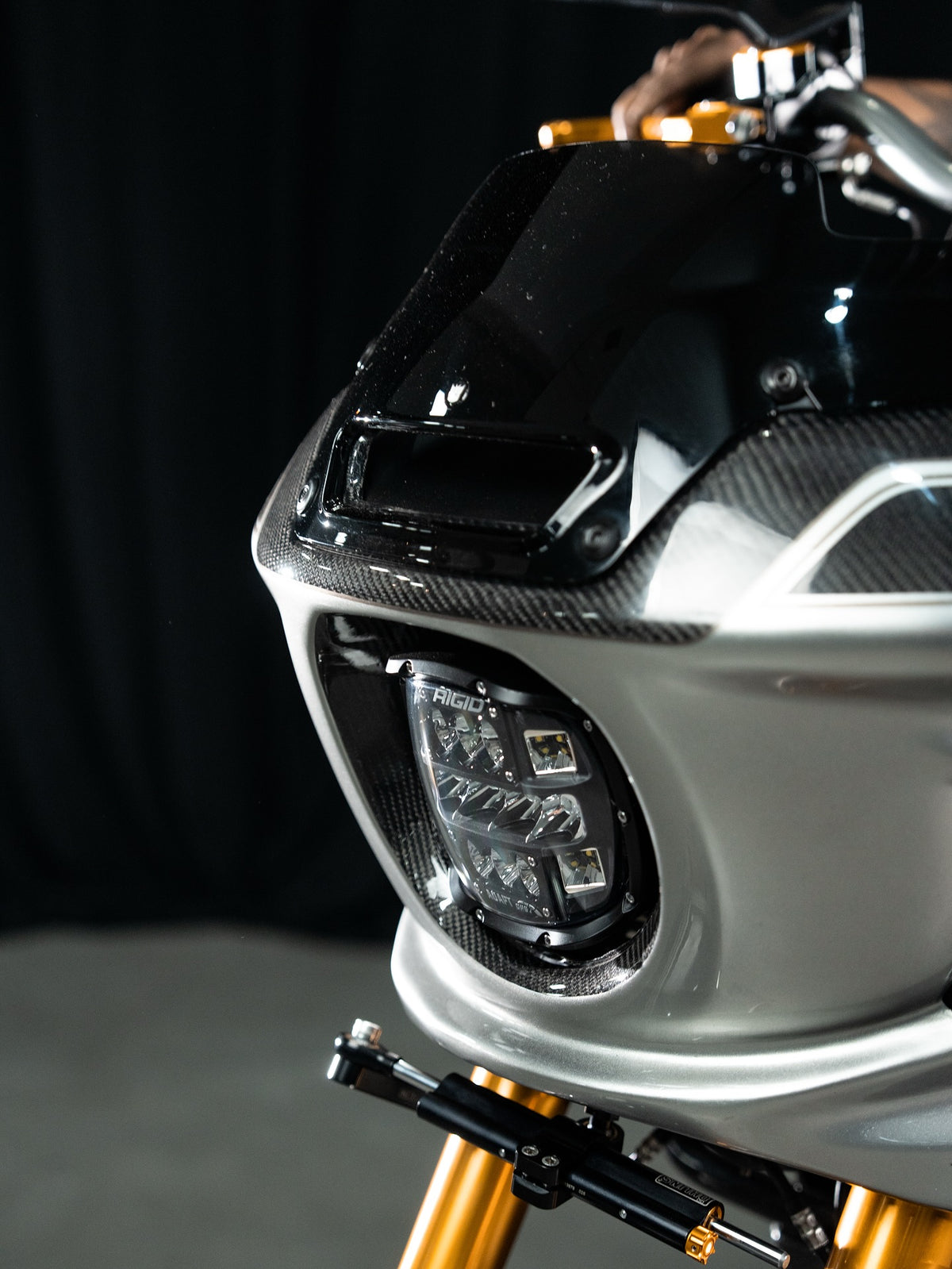 The fairing’s silver contours frame its exposed weave and headlamp.